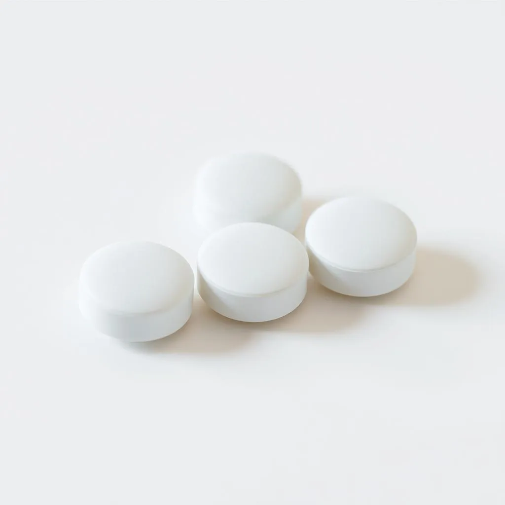 A close-up view of three white belsomra dosage tablets arranged on a clean, light-colored surface. The pills are depicted with meticulous detail, highlighting their smooth, rounded edges and slight sheen. The lighting is soft and diffused, creating gentle shadows that accentuate the tablets' form. The background is minimalist and uncluttered, allowing the medication to be the central focus of the image. The overall scene conveys a sense of simplicity, clarity, and medical precision, suitable for illustrating the "Proper Dosage and Administration of Belsomra" section of the article.